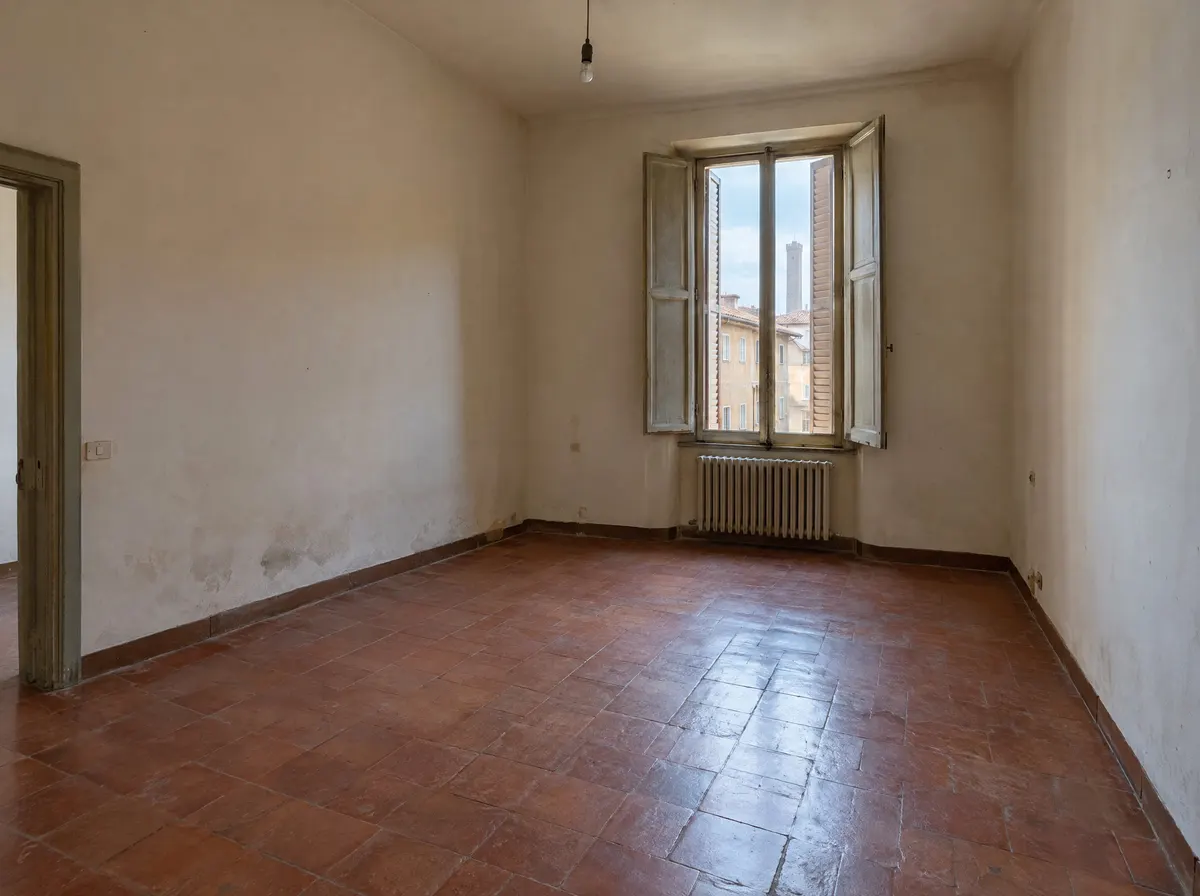 Il soggiorno vuoto, con pavimento in cotto e pareti da imbiancare